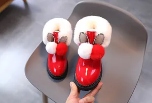 Détail de bottes d'hiver rouges pour enfants en cuir verni avec fourrure et oreilles de lapin