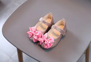 Detail von rosa Pailletten-Mädchenschuhen mit großer Satinschleife und Wellenrand