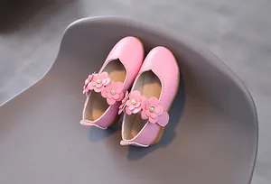 Nahaufnahme der rosa Mary Jane Schuhe mit Lederblumen und Perlen auf strukturiertem Leder