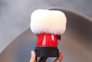 Détail de bottes neige enfant en cuir verni rouge avec col en fourrure blanche et semelle crampons