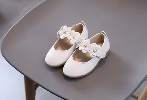 Makro-Detail weißer Mary-Jane-Schuhe aus Leder mit Blumenakzenten und Perlenmitte