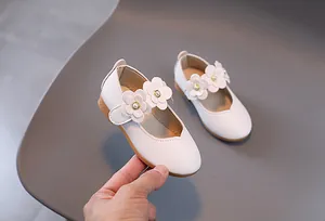 Nahaufnahme der weißen Mary Jane Kinderschuhe mit 3D-Blumen und Perlenverzierung