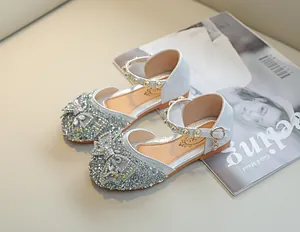 Détail de chaussures de princesse à paillettes argentées avec nœud strass et breloque cœur