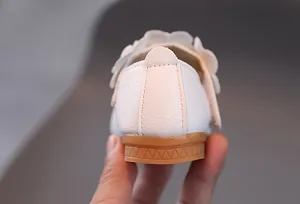 Nahaufnahme weißer Lederschuhe für Mädchen mit Blumendekor und rutschfester Gummisohle