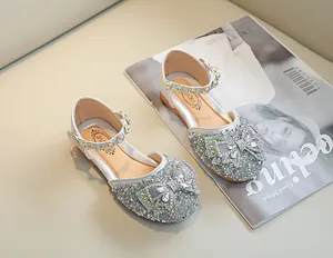 Détail des chaussures Mary Jane argentées à paillettes avec nœud strass et boucle perle