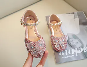 Détail de chaussure fille pailletée rose avec nœud strass et bride de perles élégante
