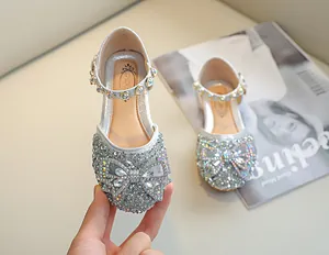 Détail macro de strass argentés et d'un nœud en cristal sur les chaussures Mary Jane fille
