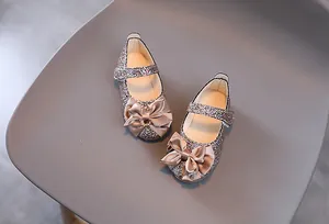 Nahaufnahme der champagnergoldenen Glitzer-Mary-Janes mit Satin-Schleife für Mädchen