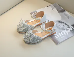 Détail de chaussures de princesse argentées à paillettes avec perles et nœuds papillon