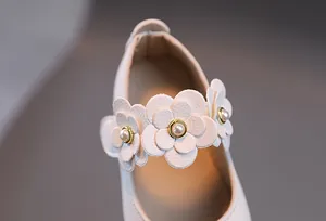 Nahaufnahme weißer Mary-Jane-Schuhe mit 3D-Lederblumen und Perlenverzierung