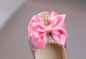 Makroaufnahme von rosa Glitzer-Finish und Satinschleife auf Mädchen-Prinzessin-Schuhen