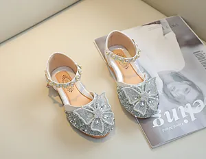 Détail de chaussures de princesse argentées pour filles avec nœud en strass et bride perle