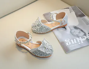 Détail de chaussures de princesse à paillettes argentées avec grand nœud, perles et strass
