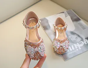 Détail de chaussure princesse rose doré avec nœud en strass et bride en perles