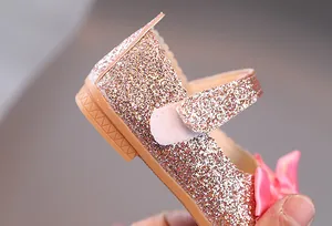 Detailansicht der rosa Pailletten-Textur und Satinschleife auf Mädchen-Schuhen