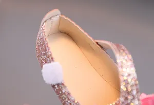 Nahaufnahme von rosa Glitzerstoff und weißem Bommeldetail an Mädchen-Prinzessinenschuhen