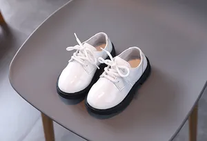 Detail of white glossy children shoes with black rubber soles and lace-up design