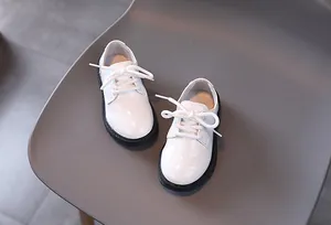 Close-up of white patent leather boys derby shoes with non-slip thick rubber soles