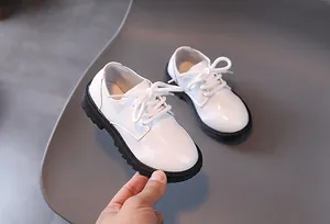 Detailed view of white patent leather boys dress shoes with durable black rubber soles
