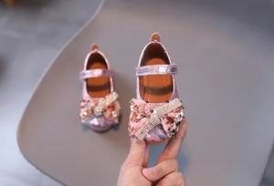 Détail de chaussures de princesse roses à paillettes avec nœud et bride en strass