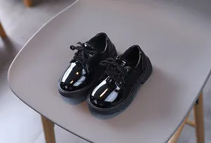 Close-up of black patent leather kids' dress shoes with laces and anti-slip rubber soles