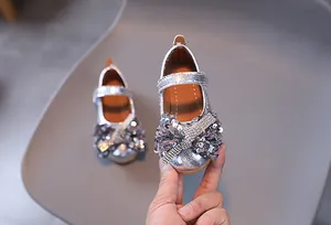 Détail de chaussures de princesse argentées à paillettes avec noeud en strass et velcro