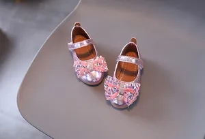 Dettaglio di scarpe da principessa rosa glitterate con fiocco di paillettes e strass