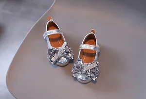 Détail de chaussures princesse fille argentées avec paillettes, nœud strass et velcro