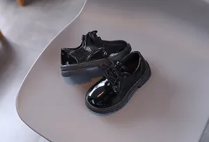Detail of boys' black patent leather oxford shoes with textured side panels and thick soles