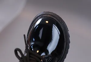 Close-up of black patent leather kids oxford shoes showing glossy finish and stitching