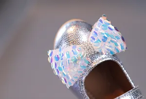 Dettaglio scarpe glitter argento con fiocco di paillettes e strass per bambina