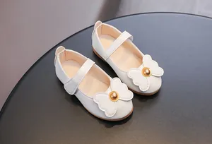 Détail de chaussures Mary Jane blanches avec nœud perlé doré et cuir grainé