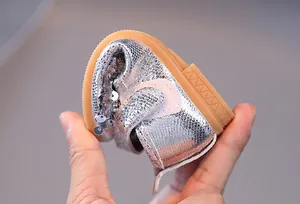 Gros plan d'une chaussure enfant argentée à paillettes avec semelle souple
