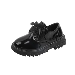 Close-up of boys black patent leather lace-up shoes with snake texture and thick rubber sole