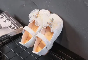 Détail de chaussures Mary Jane tressées blanches avec nœud en dentelle, perle et lapin