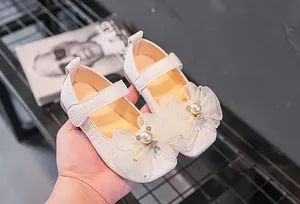 Détail de chaussures princesse blanches avec nœud en dentelle et ours en strass