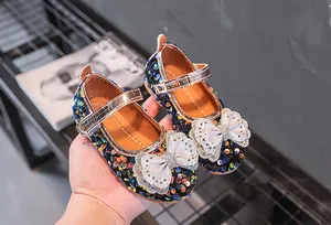 Detail von Mädchen Mary Janes mit bunten Pailletten und einer großen weißen Schleife mit Strass
