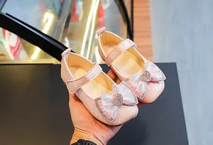 Close-up of pink Mary Jane shoes for girls with woven texture and rhinestone bow