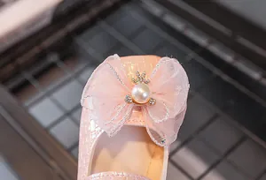 Détail d'une chaussure de princesse rose avec nœud en maille et décoration de couronne