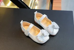 Detail of white girls Mary Jane shoes with lace bow and sparkling heart diamond buckle