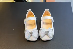 Detail of white girls Mary Jane shoes with textured faux leather and sequined bow accent