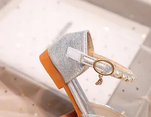 Détail de chaussures de princesse argentées à paillettes avec perles et pendentif coeur