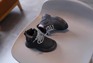 Detail of kids black combat boots with side zipper, thick rubber sole and fashion patch