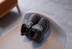 Detailed view of kids' black lace-up combat boots with thick non-slip gear soles
