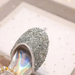 Gros plan de chaussures princesse pour filles avec paillettes argentées, strass et perles