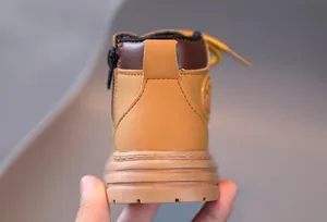 Close-up of yellow leather kids boots showing the durable side zipper and anti-slip sole