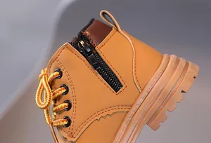 Close-up of yellow children's boots showing side zipper, sturdy stitching and woven laces