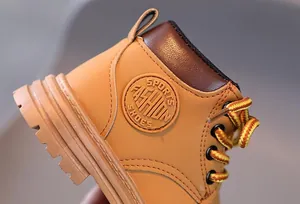 Detailed view of kids' classic tan boots featuring sports fashion leather patch and laces