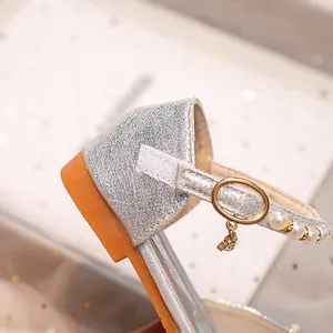 Détail de chaussures Mary Jane argentées pour filles avec perles et breloque dorée