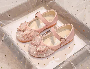 Detail of pink princess shoes featuring a large pearl and rhinestone studded bow ornament